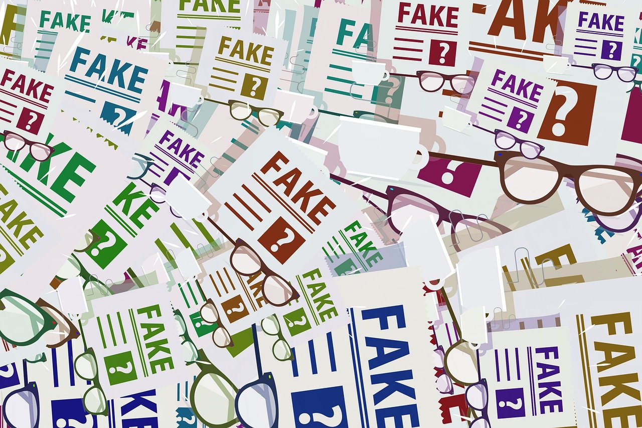 A collage of numerous papers of different sizes with the word “Fake” and a question mark printed. On them are scattered a bunch of eyeglasses