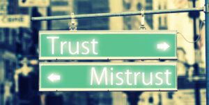 Green and white street sign that says “Trust” and “Mistrust.” The “Trust” sign has a white arrow pointing to the right, and the “Mistrust” sign has a white arrow pointing to the left.