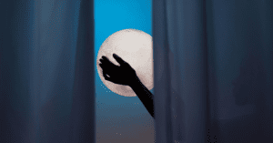 Silhouette of a person’s hand standing behind a curtain against the full Moon.