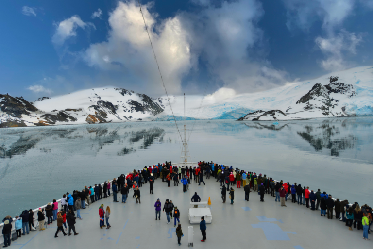 Tourists watching the view of the Arctic Ocean and frozen mountains from the deck of a polar cruise ship.
