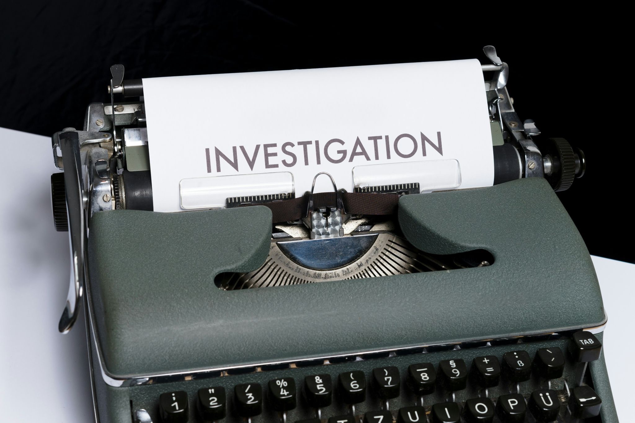 typewriter with a sheet of paper inserted into it with the inscription "Investigation"